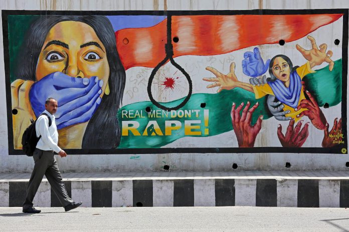 A man walks past a graffiti depicting a message in protest against rape, in Jammu