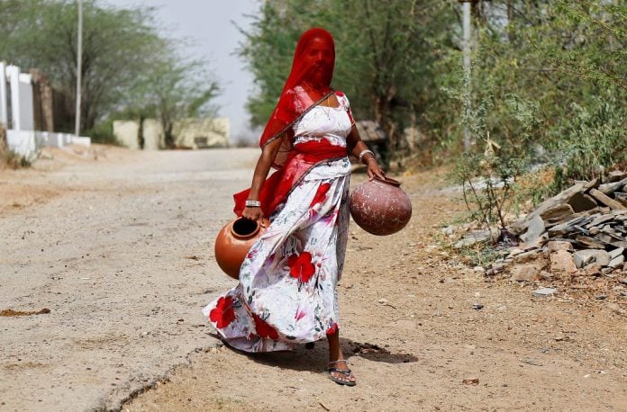 A woman carries earthen pots to fill them with drinking water on a hot summer day, on the outskirts of Ajmer